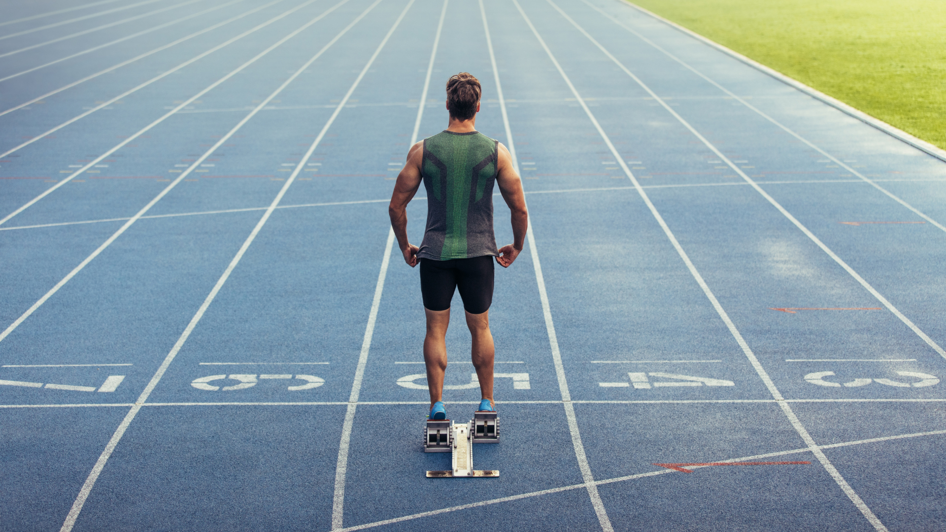 A man is standing on a track ready to run.