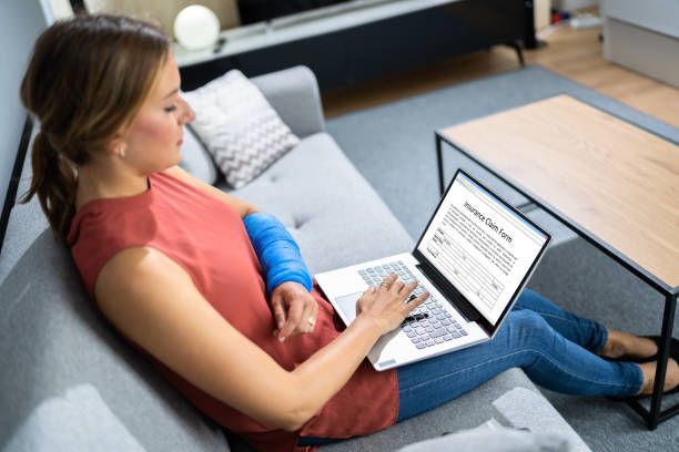A woman with a cast on her arm is sitting on a couch using a laptop computer.