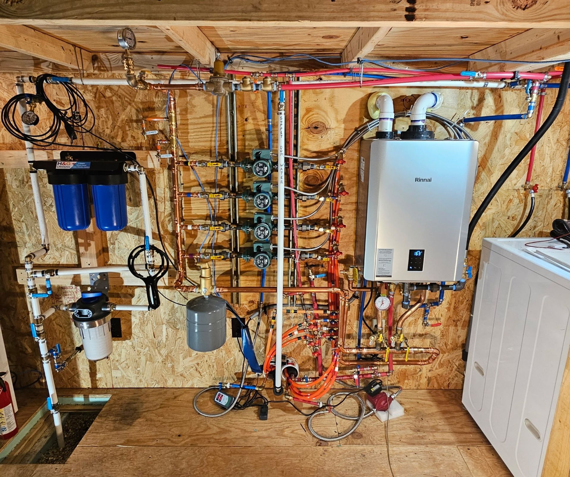 A complex wall-mounted mechanical system featuring a tankless water heater, multi-stage water filters, and copper piping.