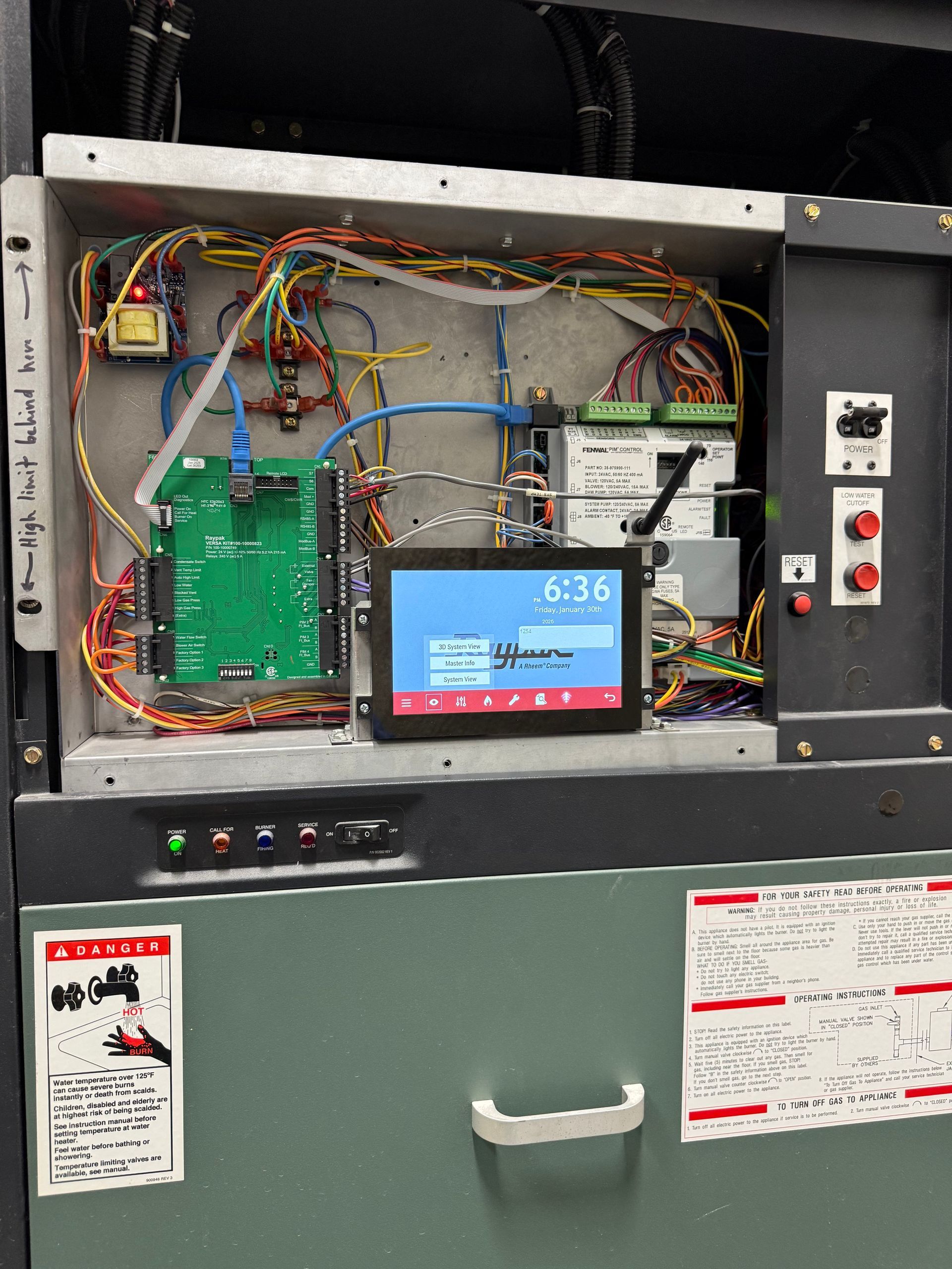 An open metal industrial control cabinet featuring a mounted touchscreen display, circuit boards, and internal wiring.