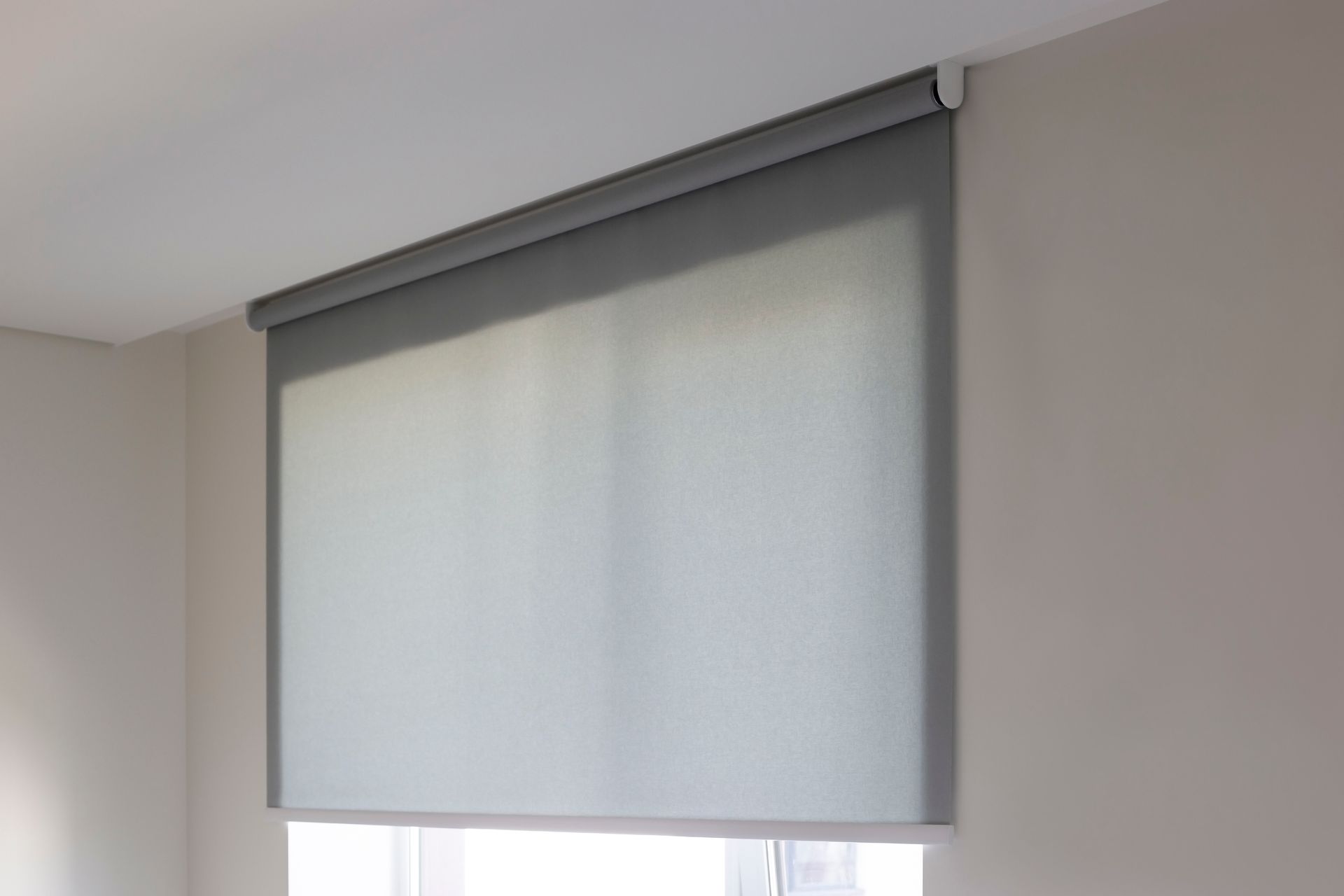 The sun is shining through the blinds on the window.