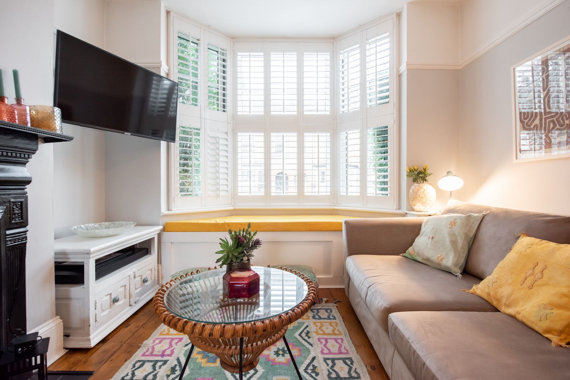 A living room with a couch , table , television and bay window.