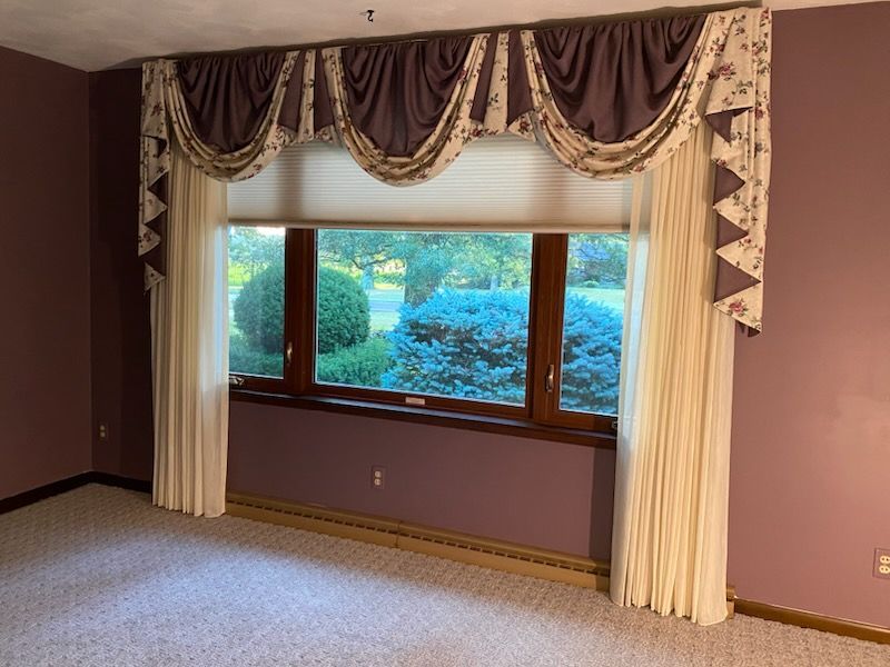 A room with brown curtains and white curtains on a window.