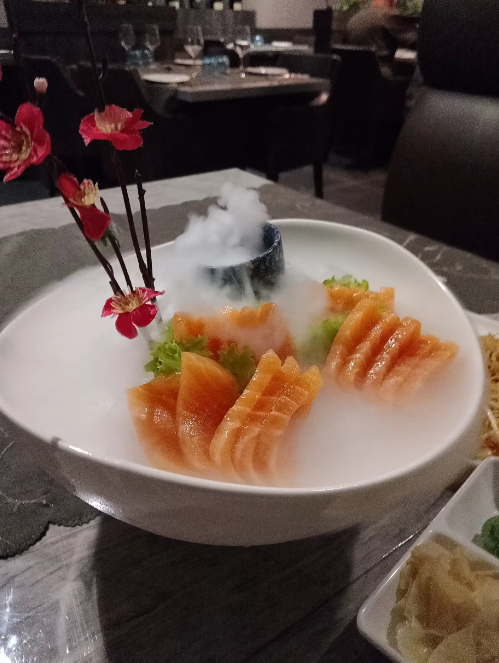 Su un tavolo di ristorante, in una ciotola bianca con fette di arancia, guarnizione verde e fiori di orchidea.
