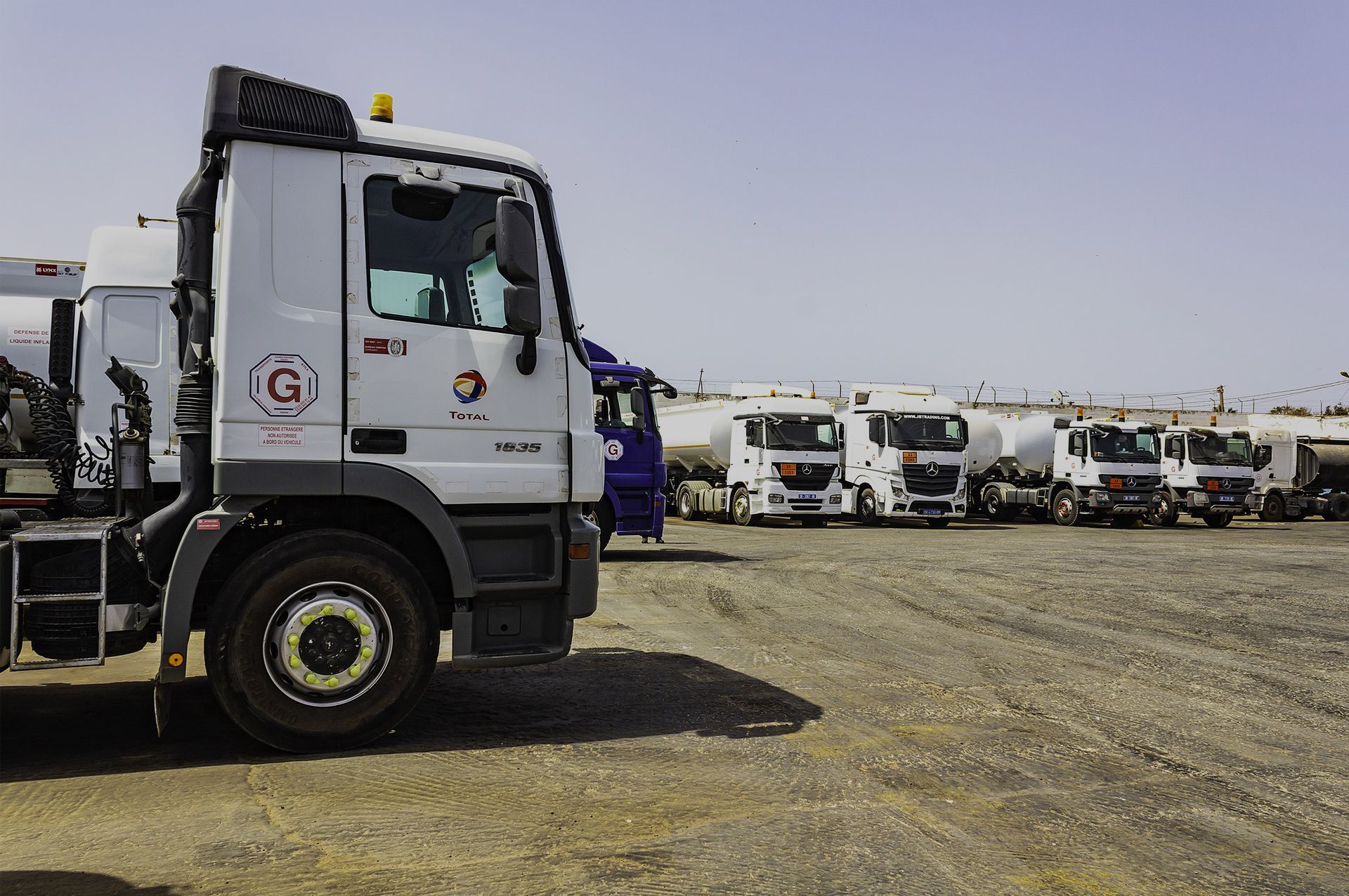 Une rangée de camions est garée dans un terrain sale.