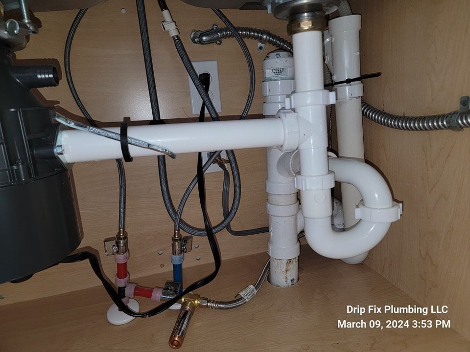 Under-sink plumbing with pipes, garbage disposal, and water lines inside a cabinet.
