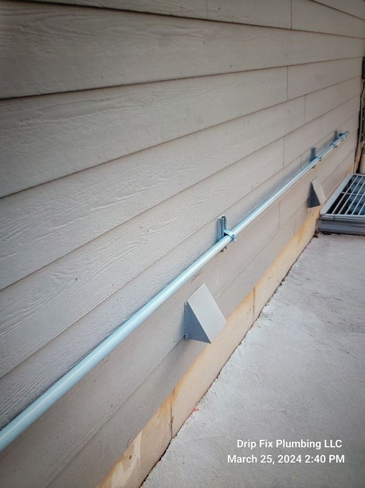 A light blue pipe installed along the side of a building, supported by gray brackets.