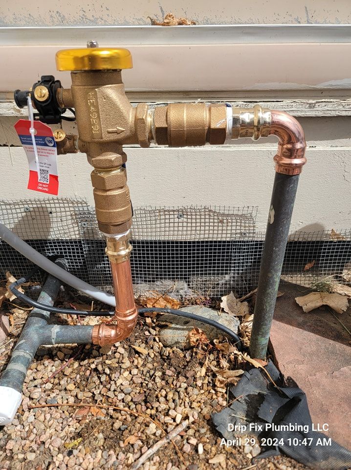 Plumbing device with copper pipes and brass valve near a building.