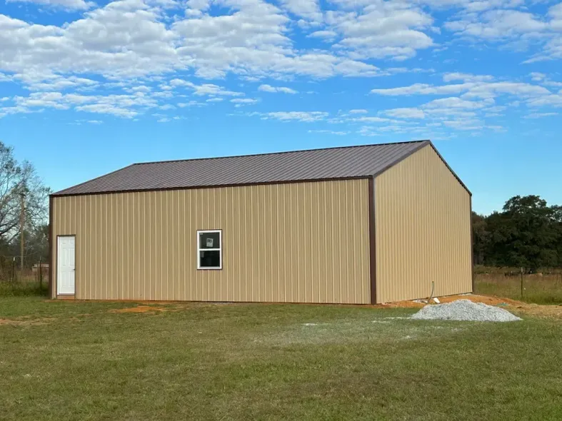 Tan metal building with brown trim, a door, and a window under a blue sky.