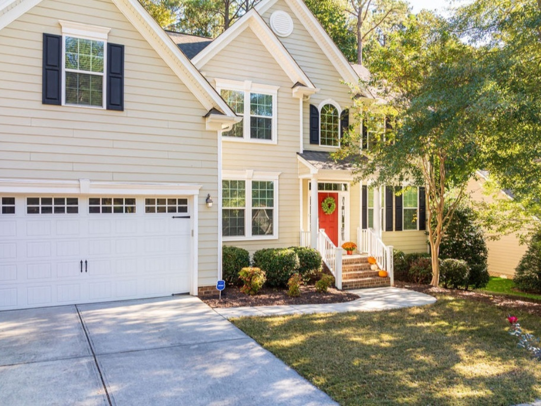 Brick house with a dark roof, arched window, and green lawn.