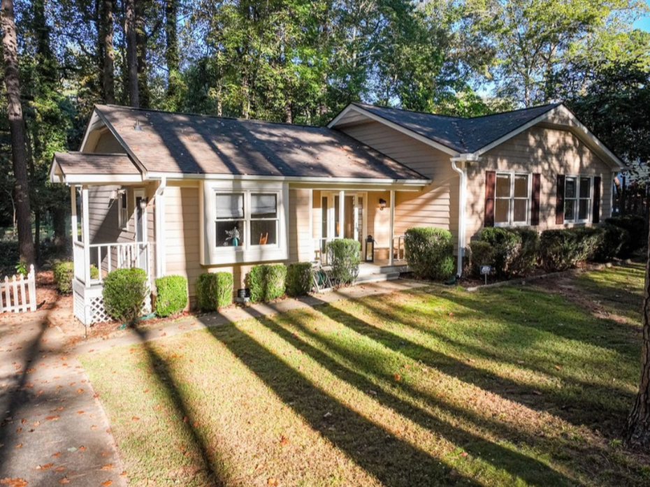 Brick house with a dark roof, arched window, and green lawn.
