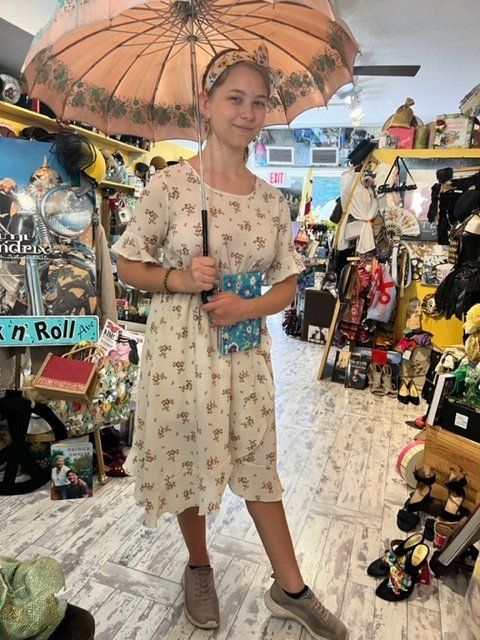 A girl in a dress is holding an umbrella in a store