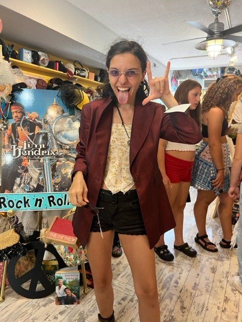 A woman sticking her tongue out in front of a sign that says rock n roll