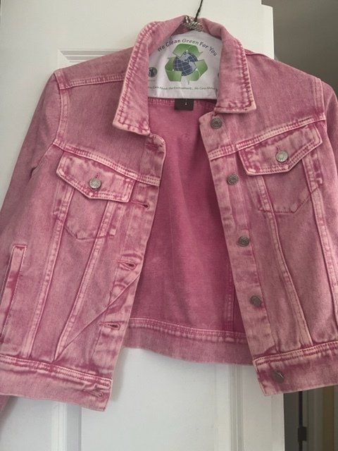 A pink denim jacket is hanging on a white door