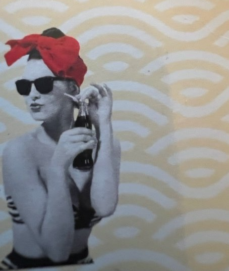 A woman wearing sunglasses and a red headband is holding a bottle of soda