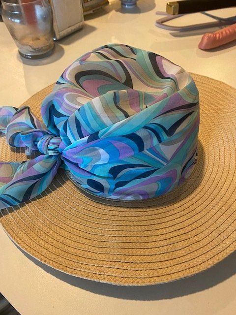 A hat with a scarf tied around it is on a table.