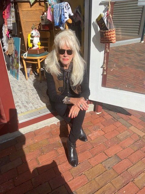 A woman is sitting on a brick sidewalk in front of a door.