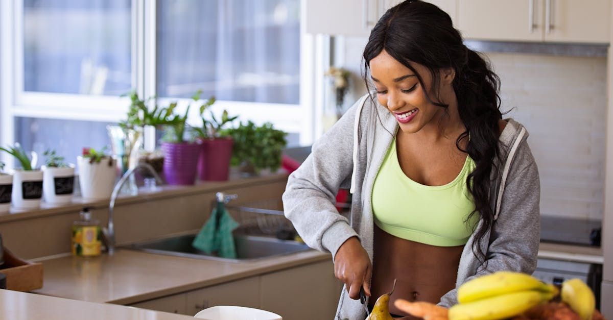 A woman is cutting a banana in a kitchen. NWL healthy habits