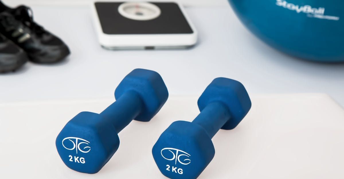 Two blue dumbbells are sitting on a white surface.