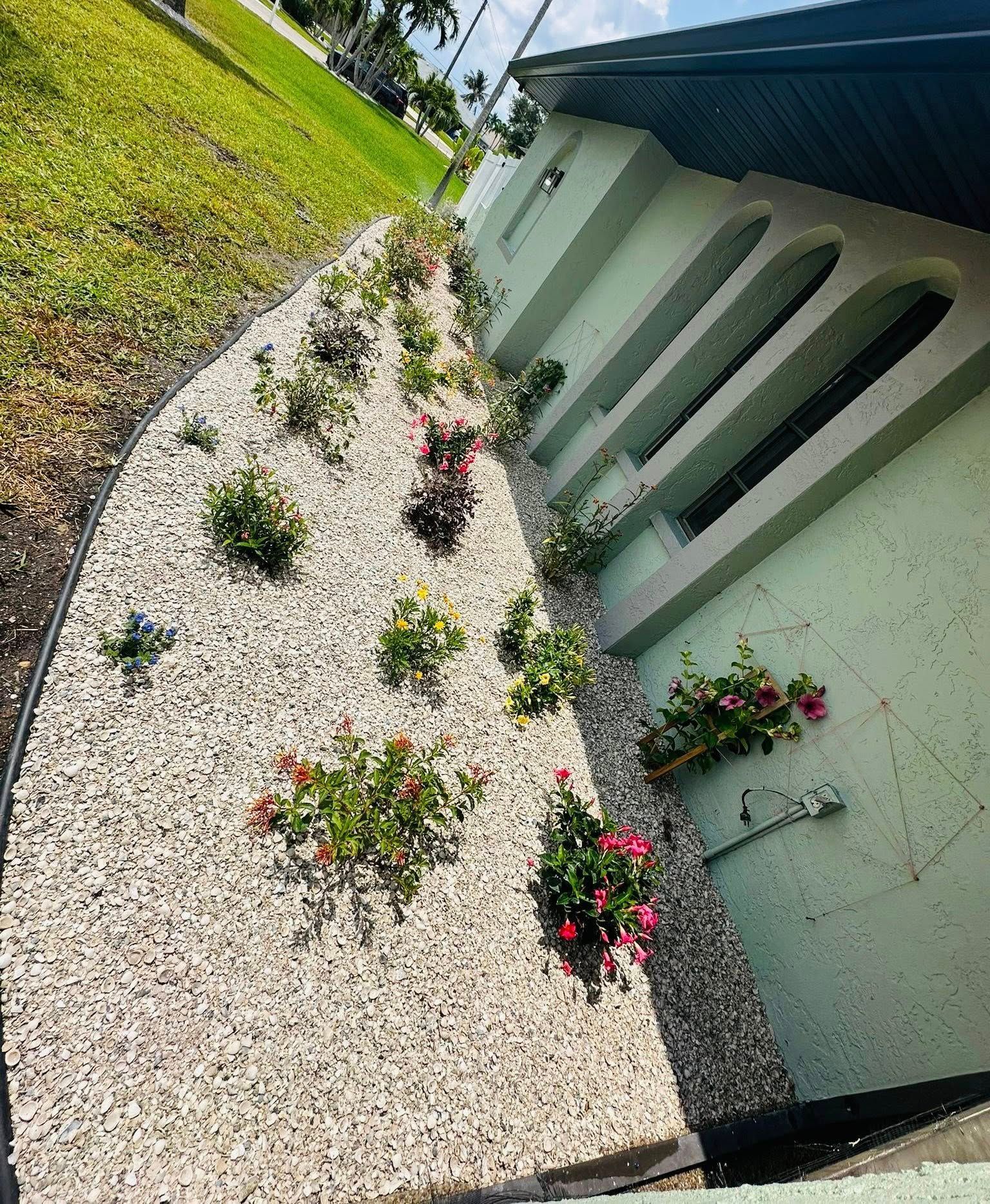 Gravel-covered flower bed along a light green building with arched windows.