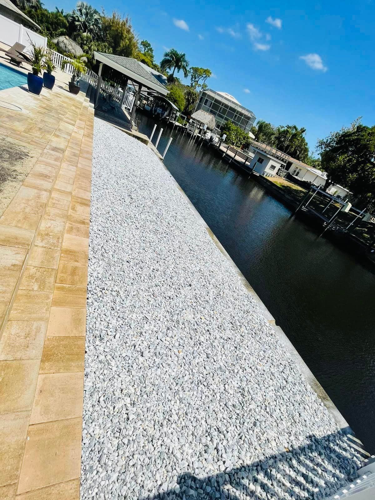 Stone seawall next to a waterway and tan patio.