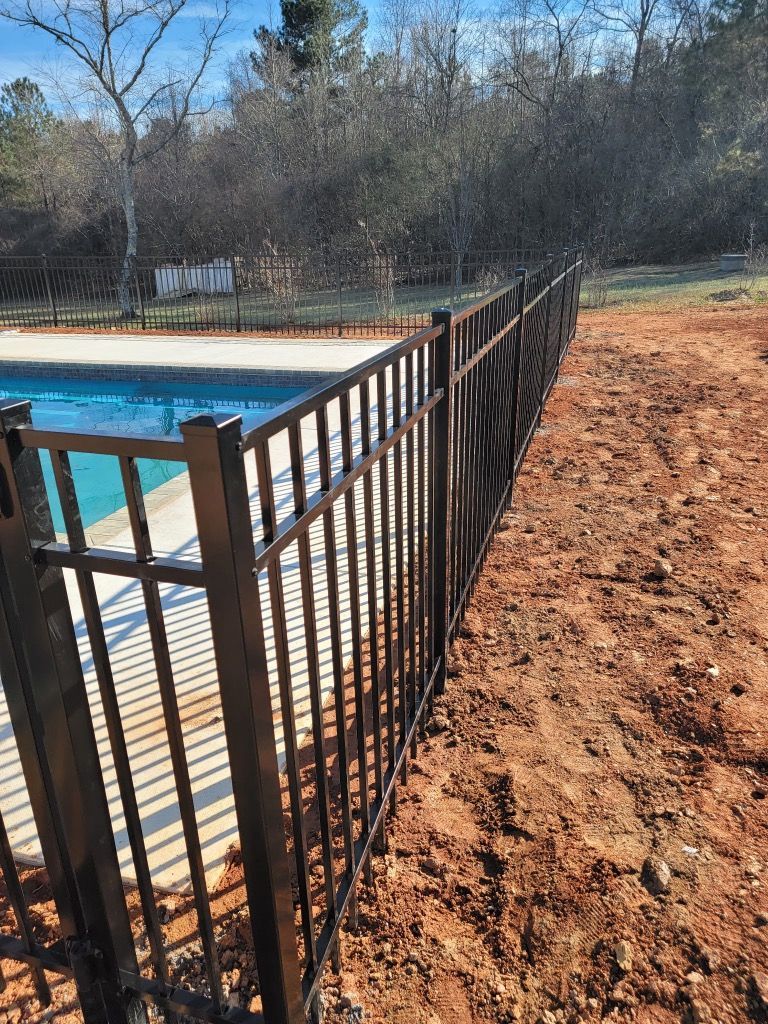 A metal fence surrounds a swimming pool in a backyard.