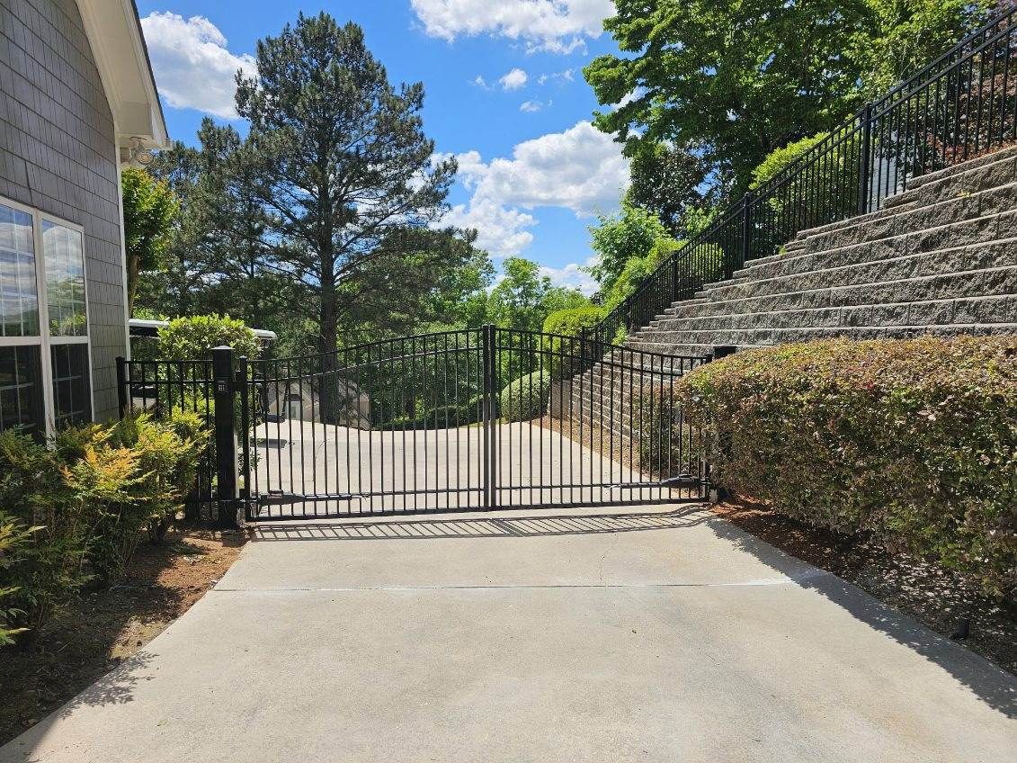 A concrete driveway with a metal gate leading to a house.