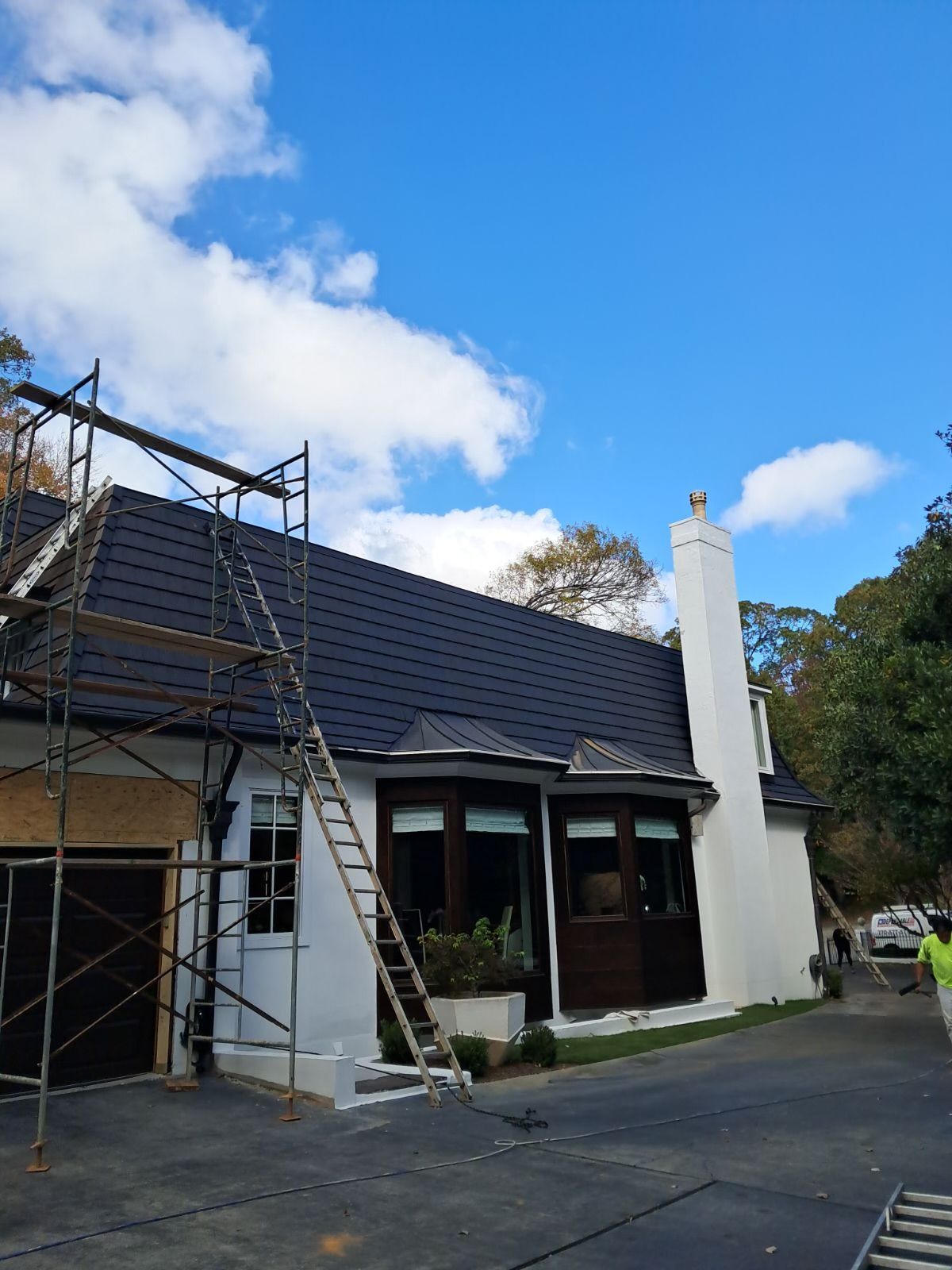 A white house with a black roof is being painted.