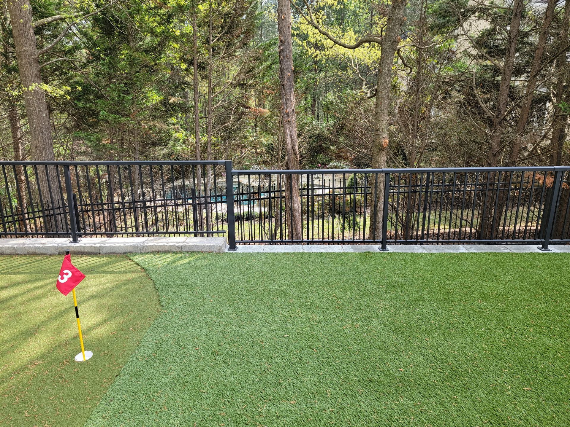 A golf course with a fence and a flag on the green.