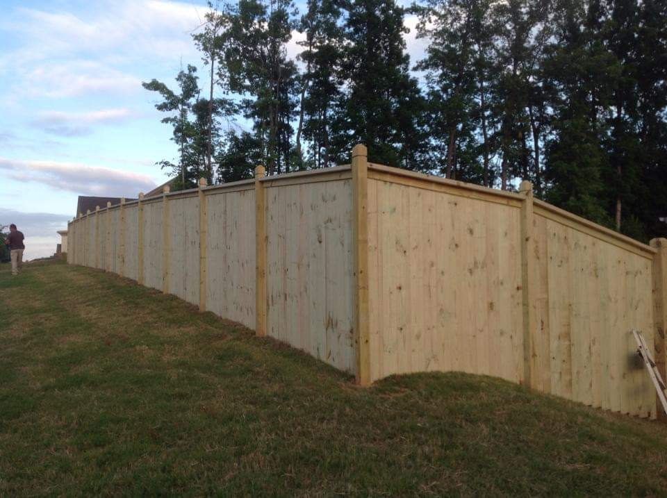 A wooden fence is sitting on top of a grassy hill.