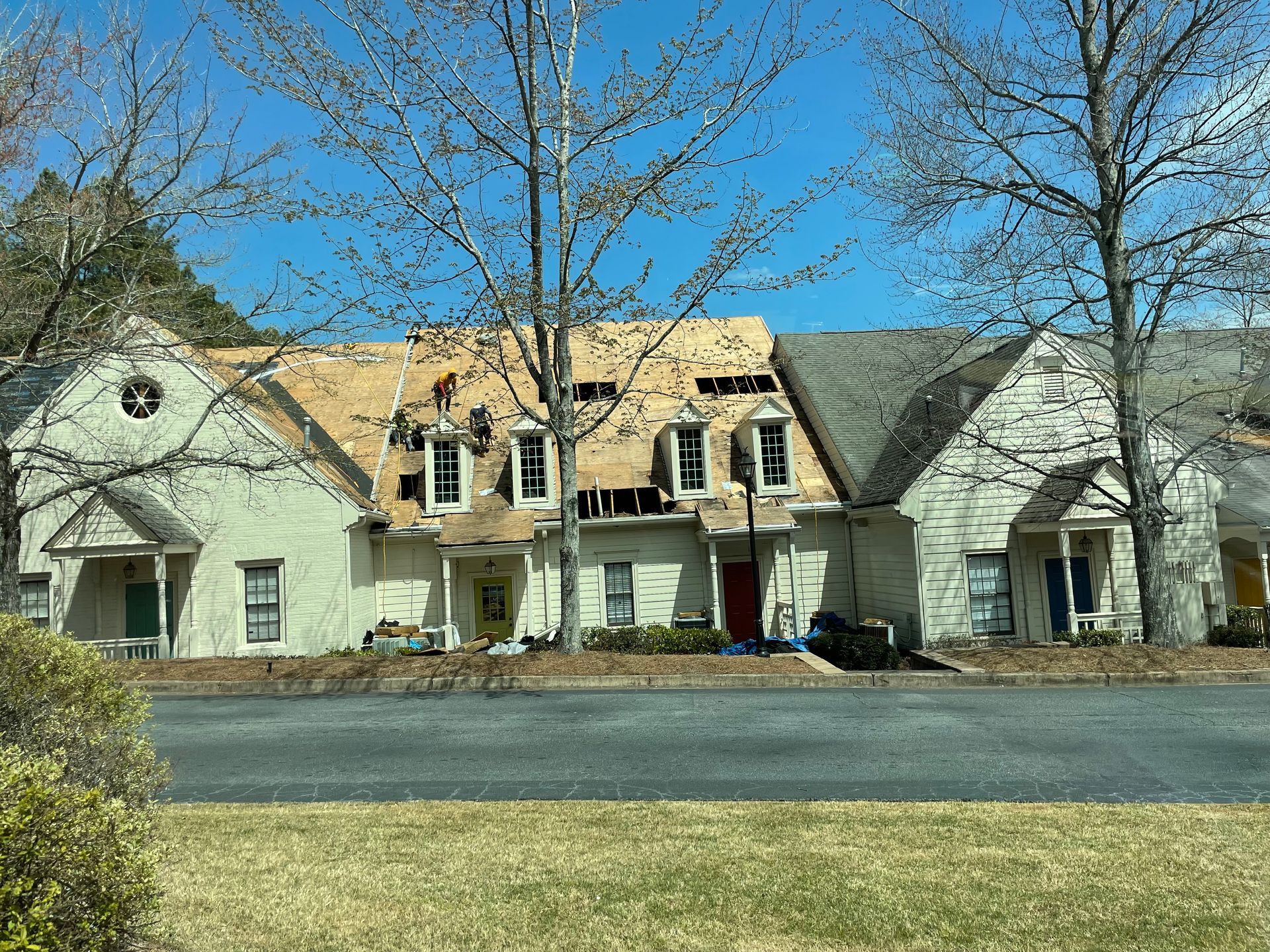 A row of white houses with a roof under construction.