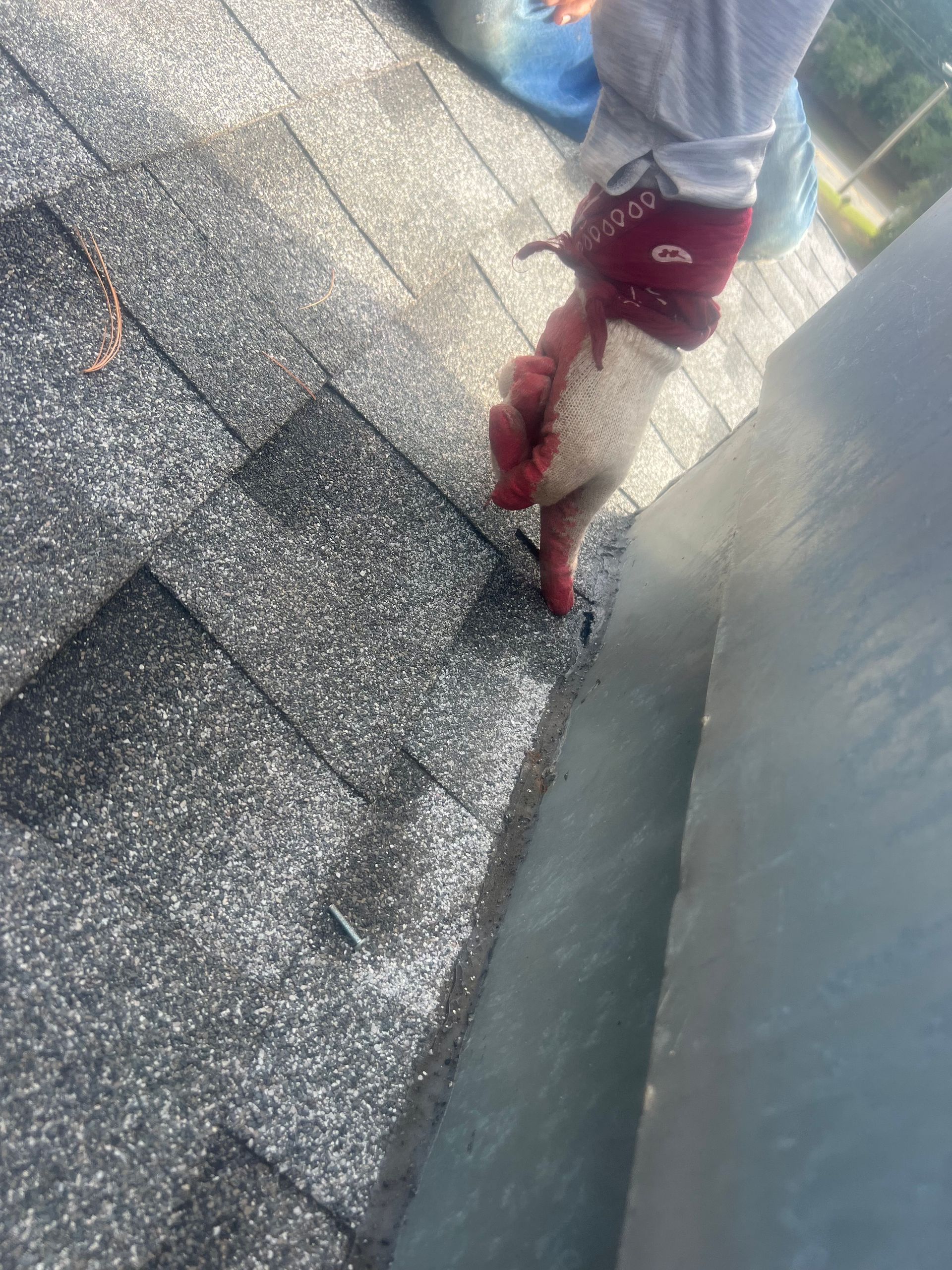 A person wearing red gloves is working on a roof.