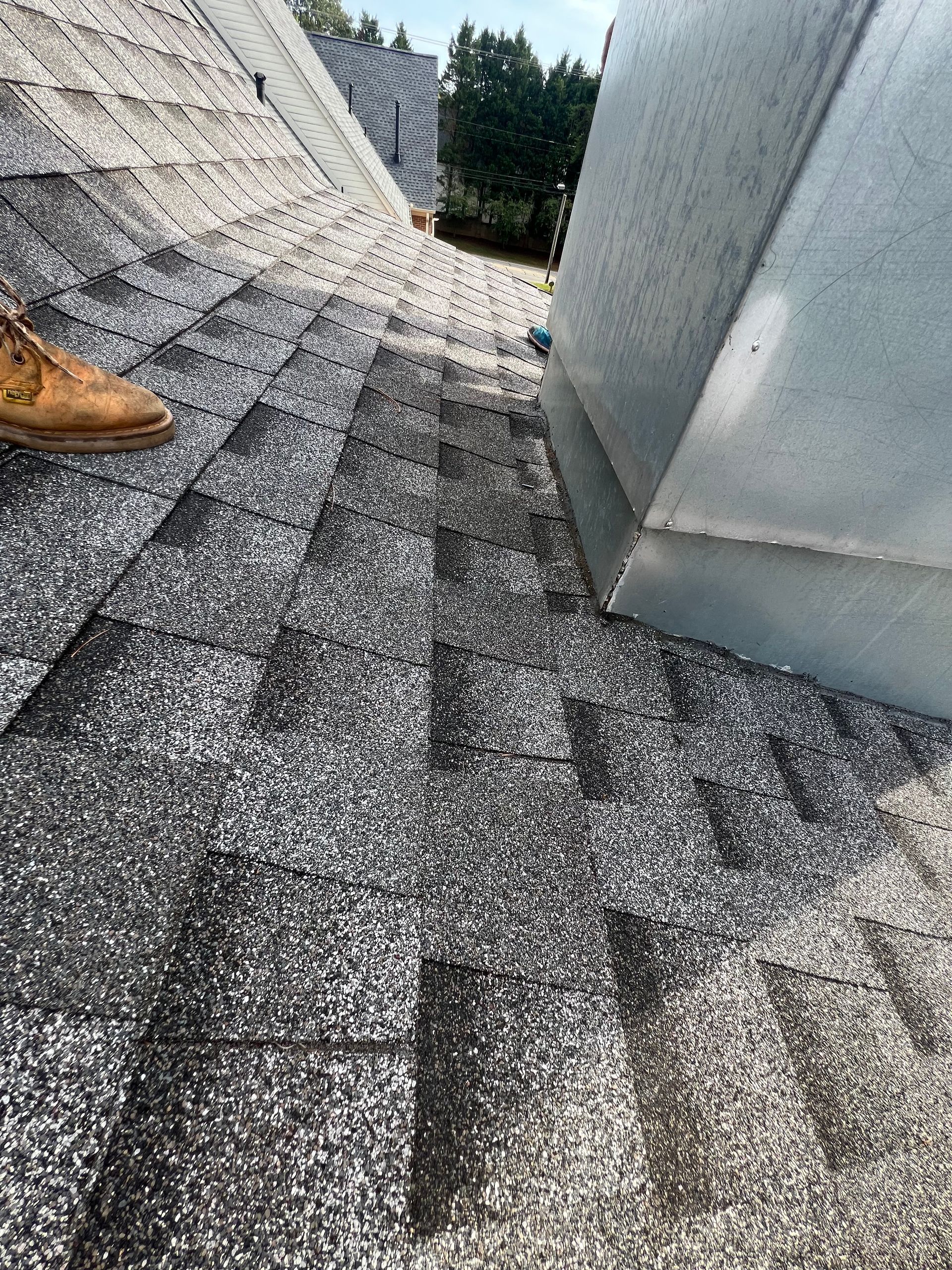 A person is standing on a roof with a pair of brown shoes on it.