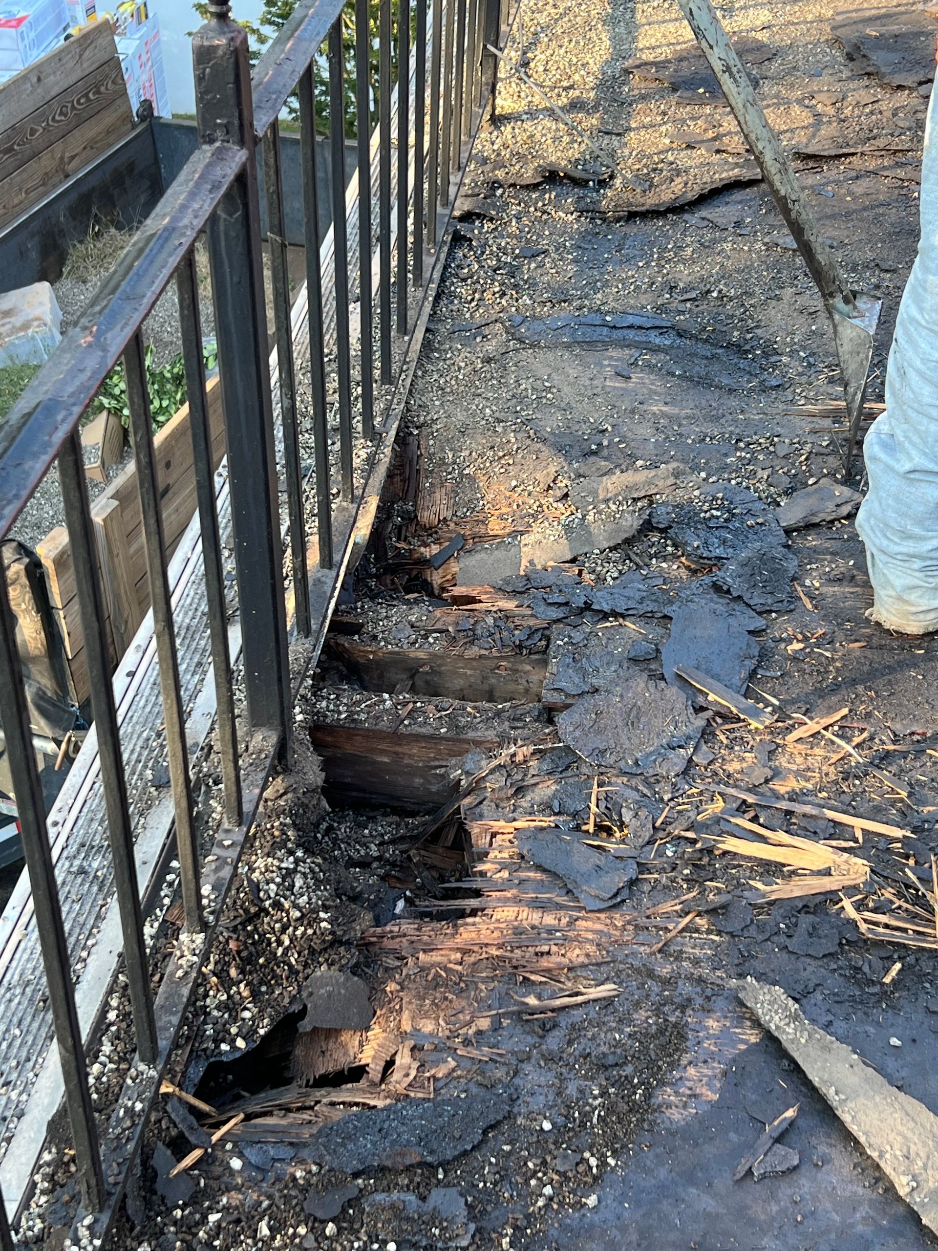 A person is standing next to a fence that has been damaged by a fire.