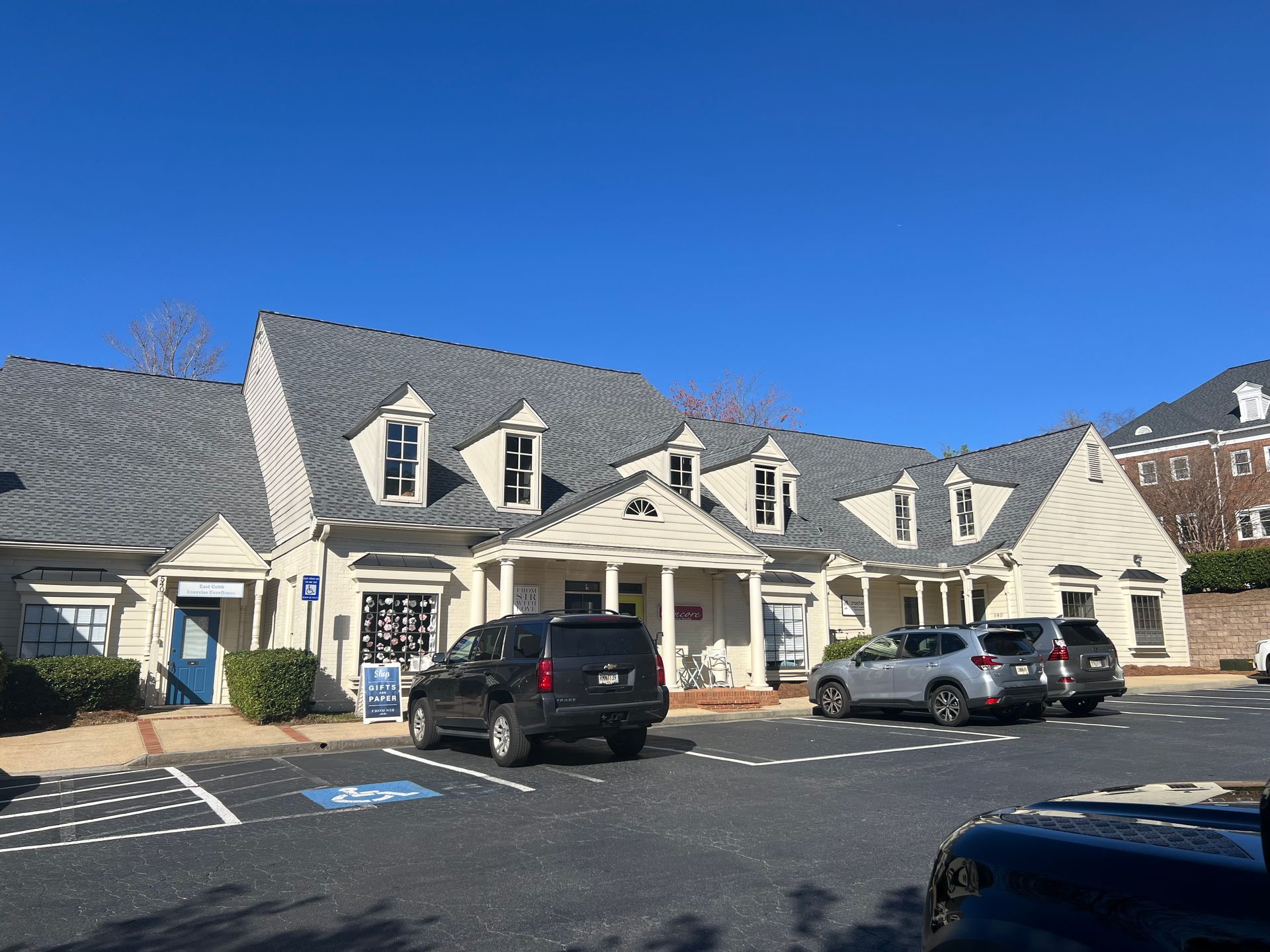 A row of cars are parked in front of a large white building.