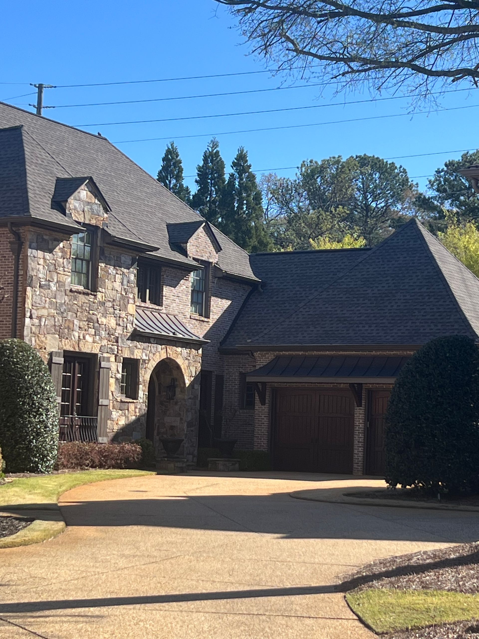 A large stone house with a gray roof and a garage