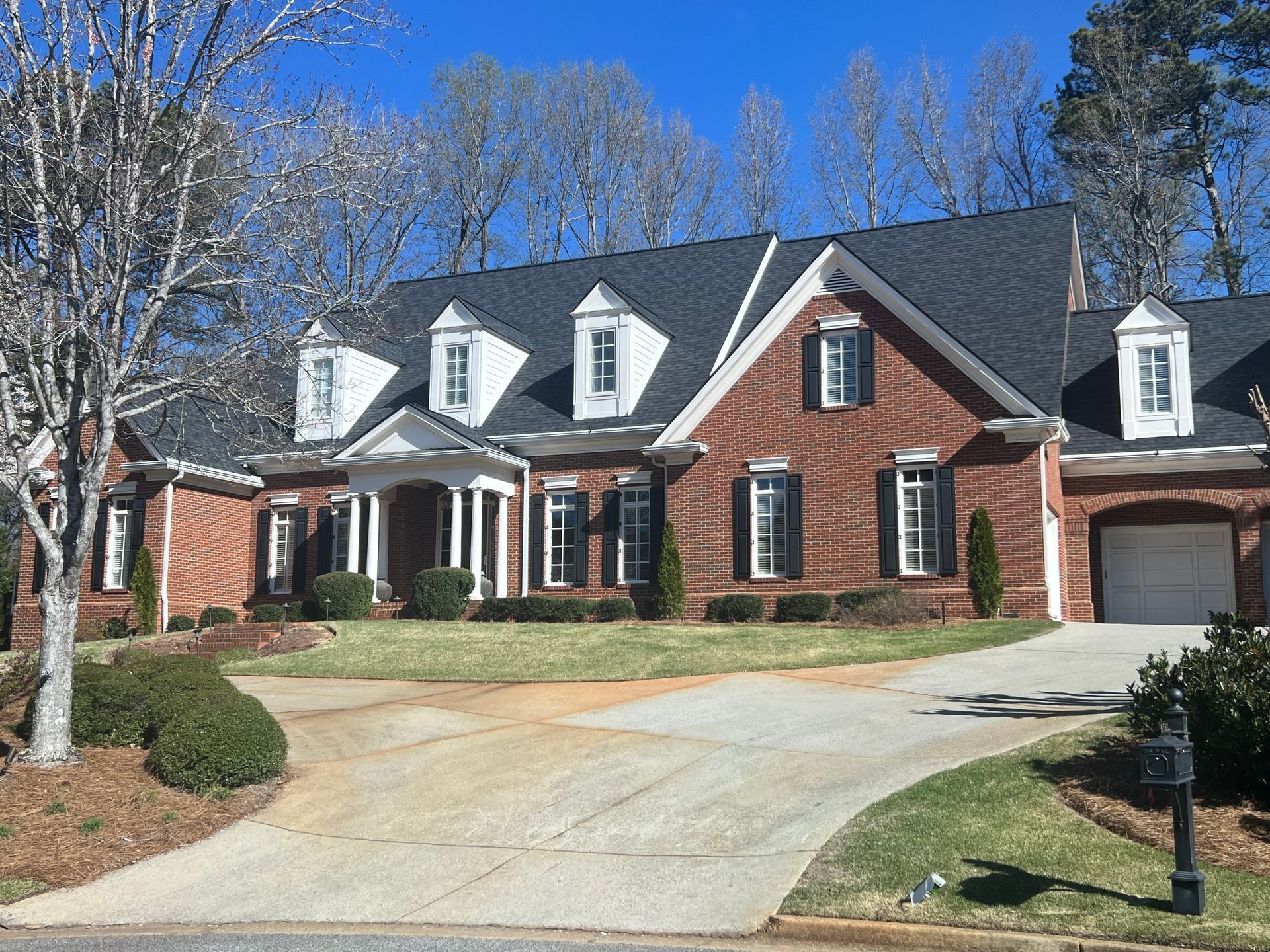 A large brick house with a black roof and white shutters