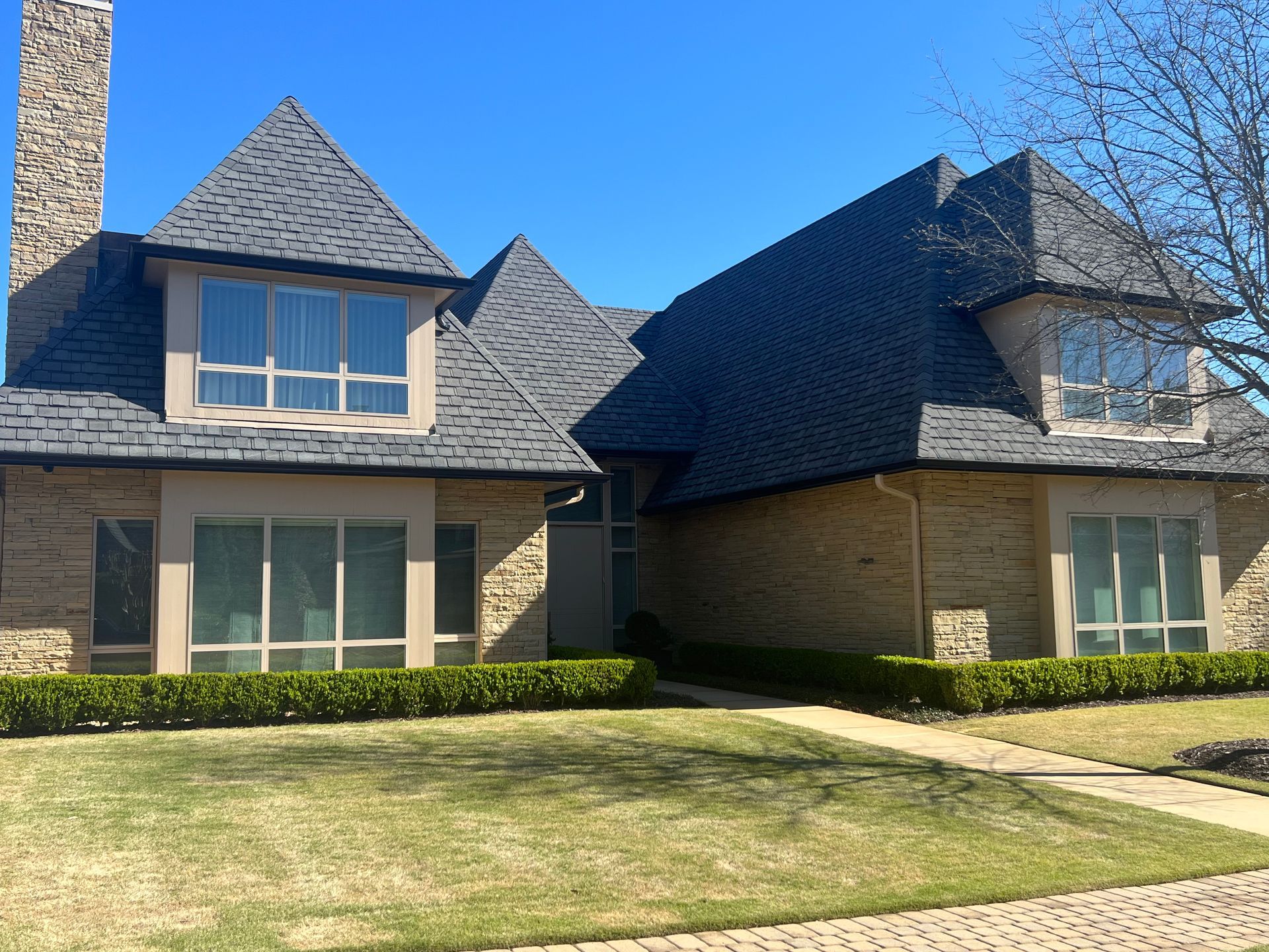 A large brick house with a gray roof and a chimney