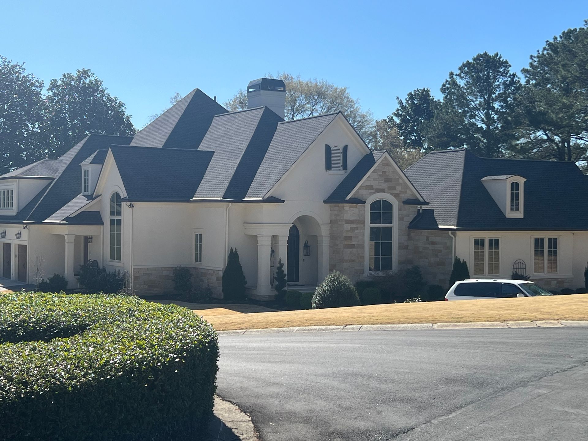 A white house with a black roof has the letter h on the front