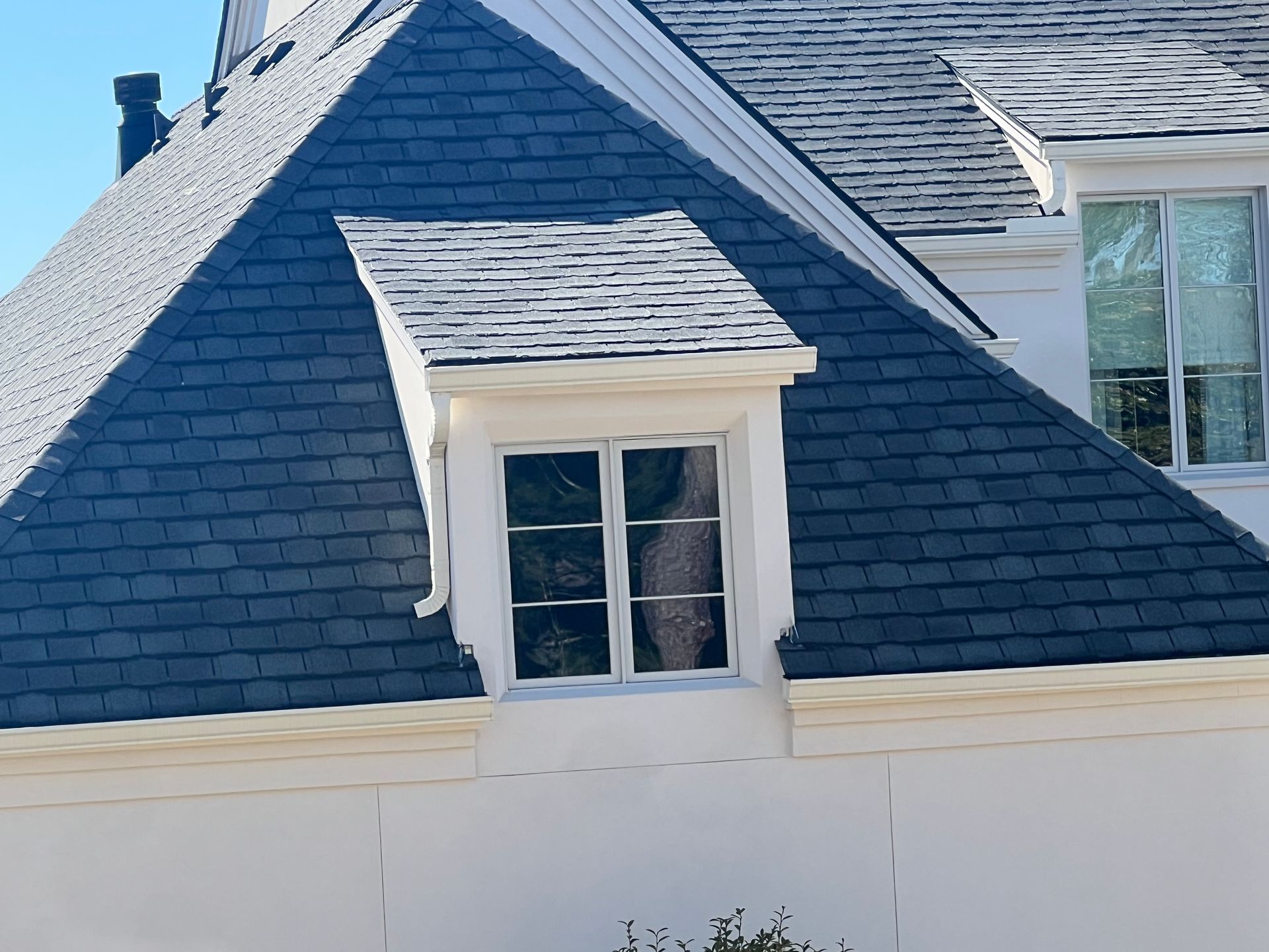 A white house with a slate roof and a window
