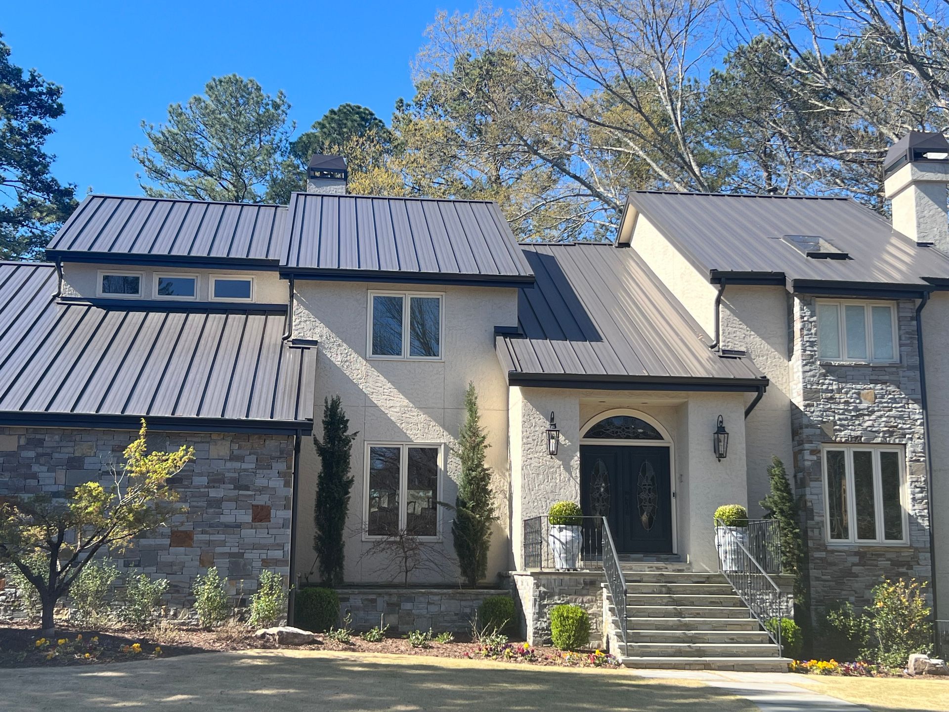 A large house with a metal roof and a stone facade