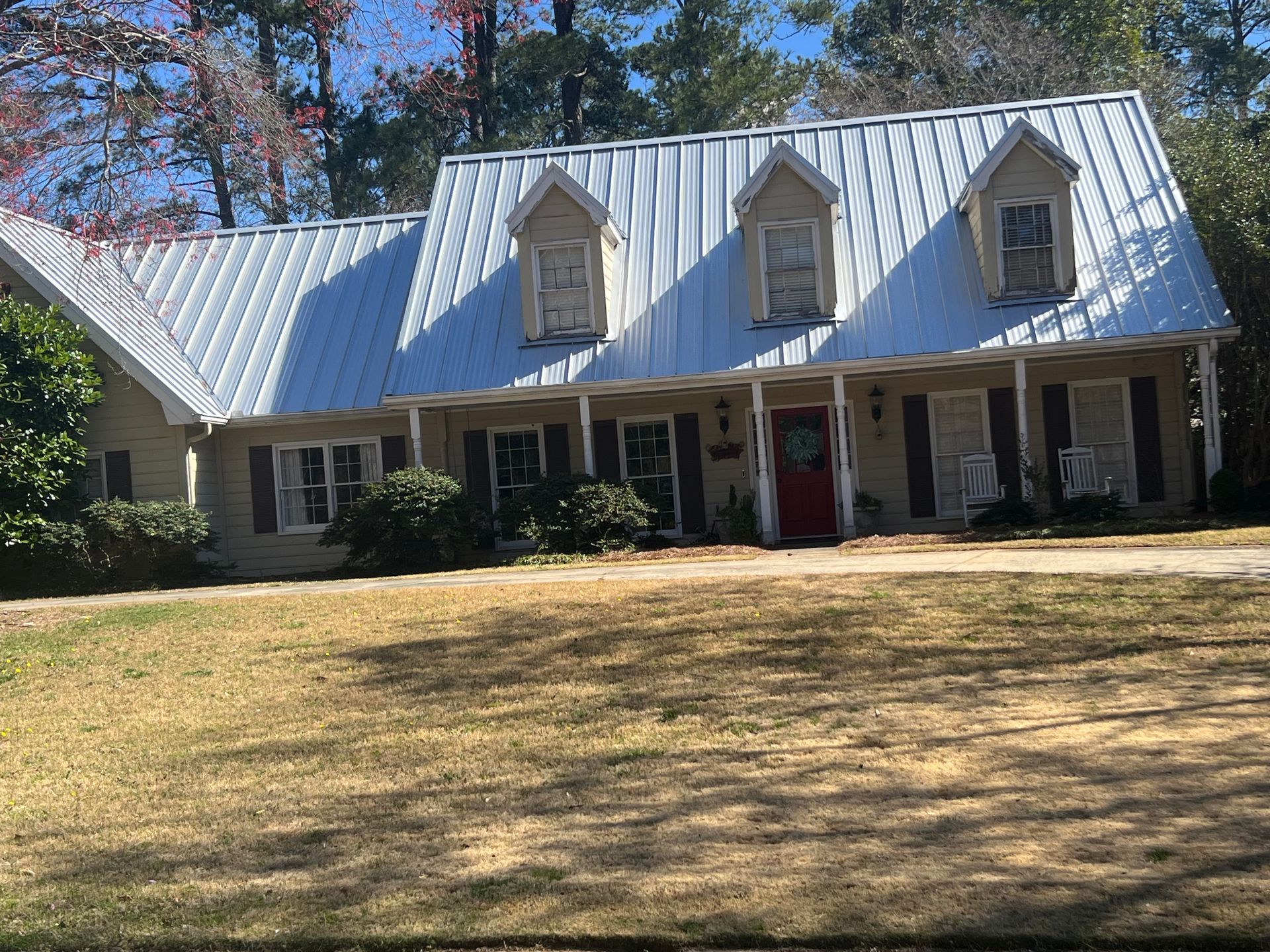 A white house with a metal roof and a red door