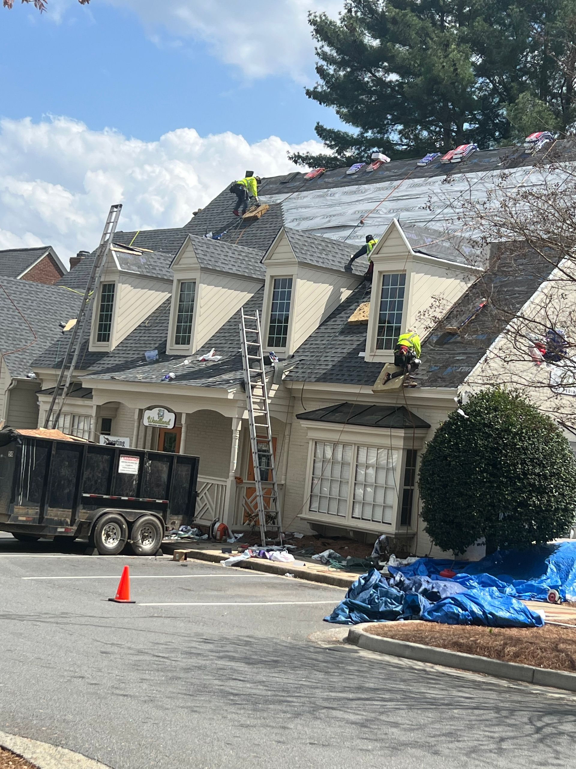 A house is being remodeled with workers on the roof.