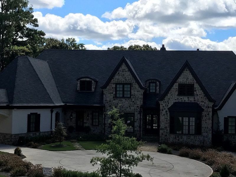 A large house with a black roof and a driveway