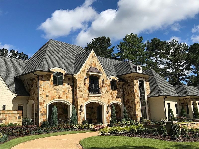 A large house with a gray roof and a driveway in front of it.