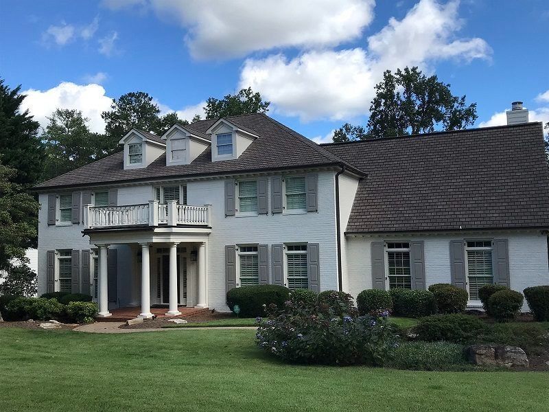 A large white house with a gray roof and shutters