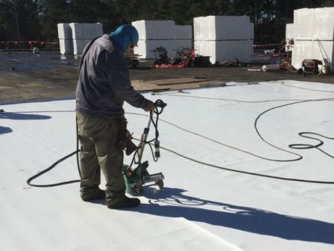 A man is working on a roof with a machine