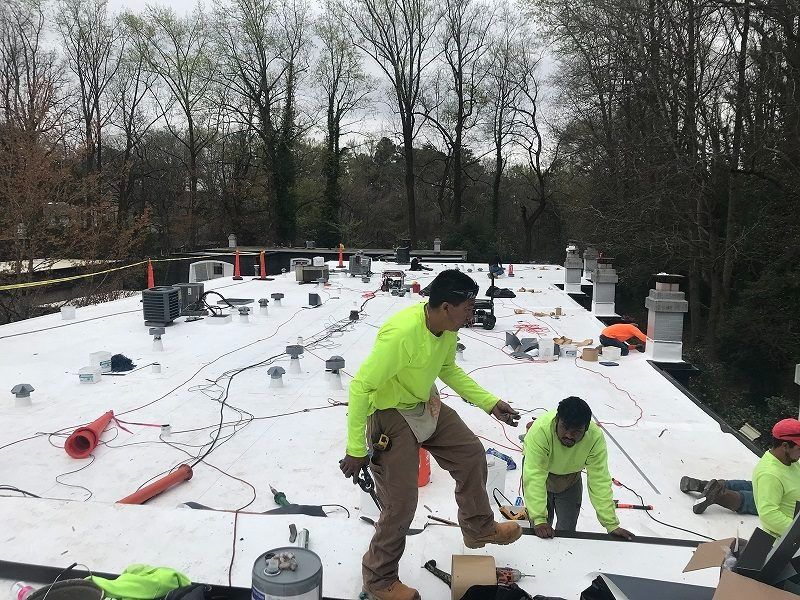 A group of men are working on a white roof.
