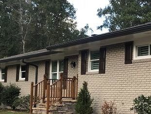 A brick house with a wooden porch and stairs.
