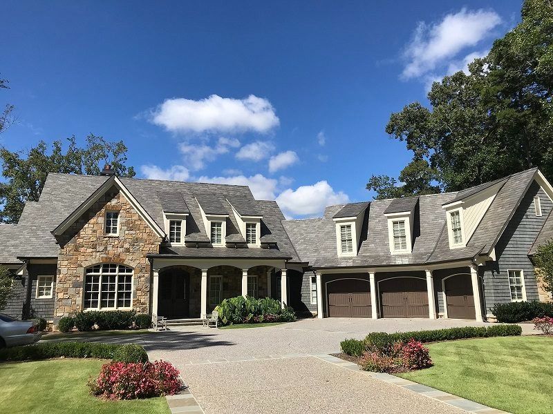 A large house with a gray roof and brown garage doors